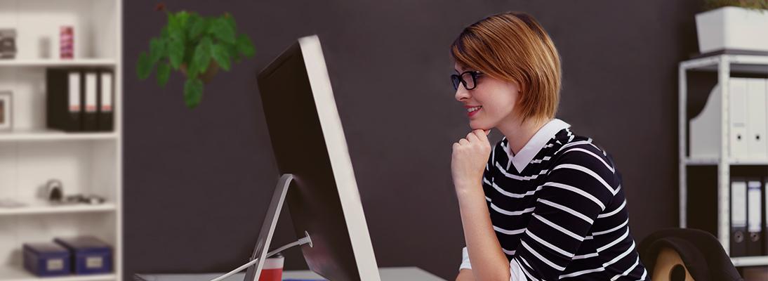Jeune femme assise devant un écran avec une interface utilisateur par Libelle DataMasking